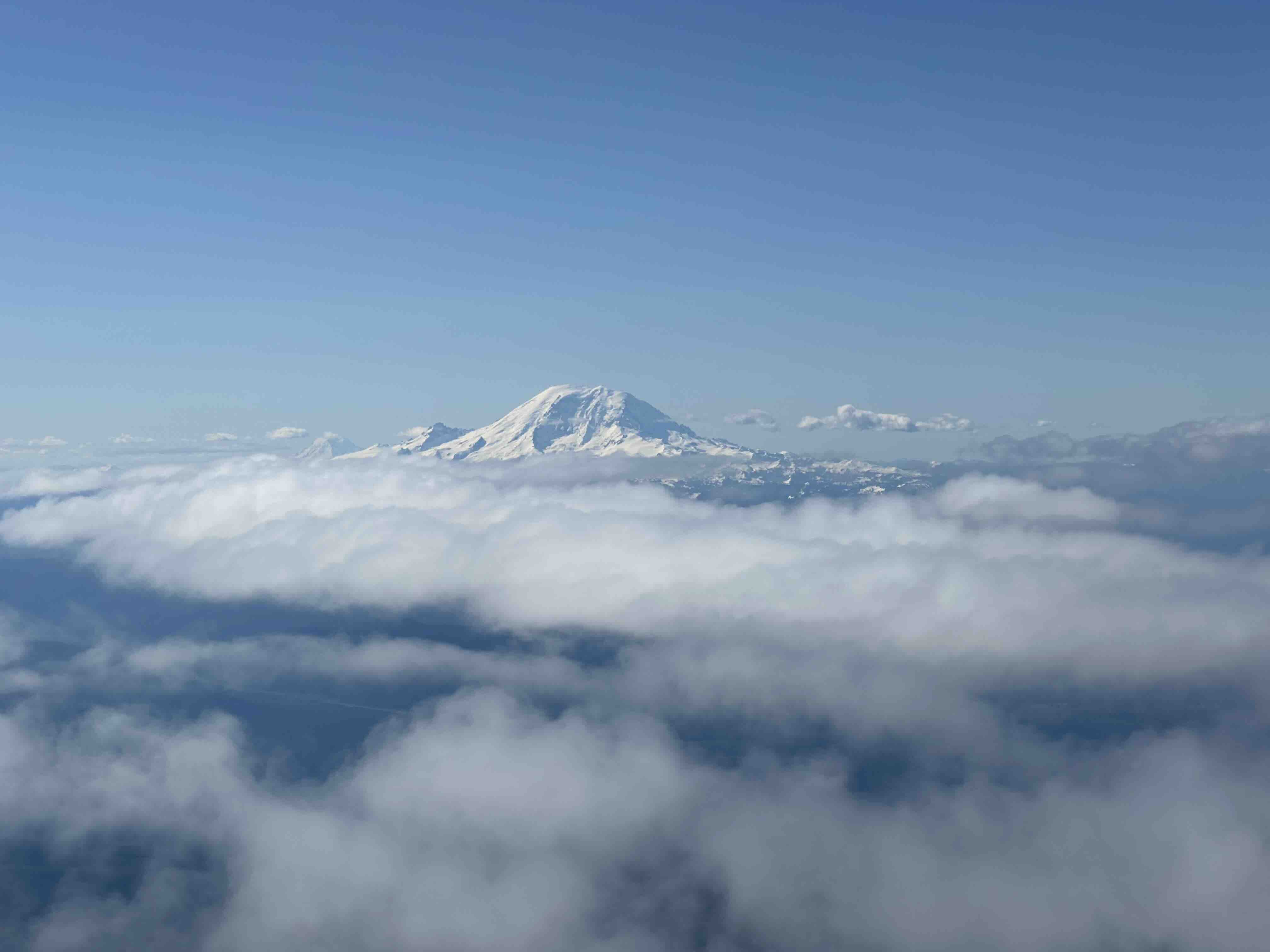 Seattle’s Mount Rainier rising about the clouds, as seen from an airplane. Photo by Adriana Villela